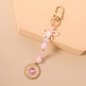 Vue détaillée du porte-clés à perles roses avec nœud en résine et breloque soleil doré