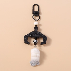 Detail of plush animal keychain featuring a mechanical claw and striped decorative beads