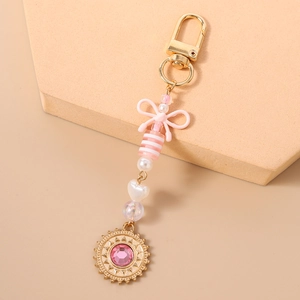 Détail d'un porte-clés à nœud rose avec pendentif soleil et perles pour sacs