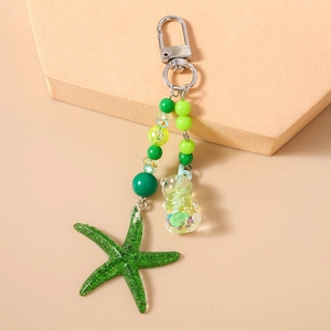 Détail d'un porte-clés à perles avec charms étoile de mer et ours vert de style marin