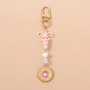 Détail du porte-clés à nœud rose avec perles et pendentif soleil doré serti d'un cristal