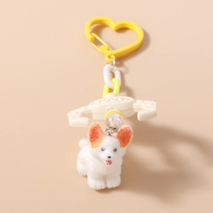 Detail of white plush dog keychain with orange ears and yellow heart-shaped plastic clip