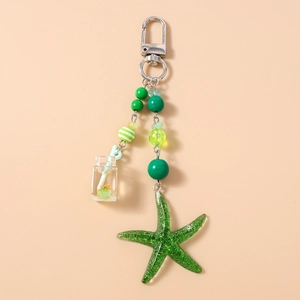 Détail du porte-clés étoile de mer verte avec perles rayées et breloque bouteille