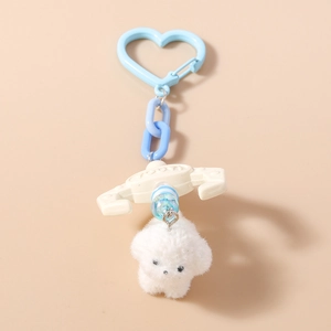 Close-up of white plush puppy keychain with heart clip and blue chain link detail
