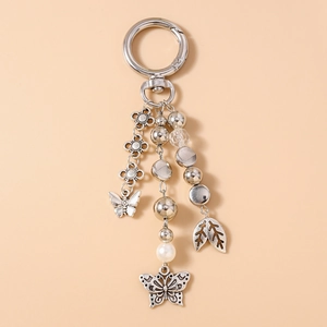 Detailed macro view of vintage silver butterfly keychain with metal leaves and beads