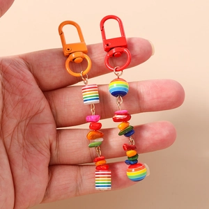 Rainbow beaded keychain with colorful stones and metal clasp held by hand on beige background