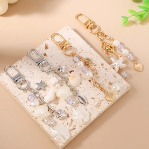 Ocean themed beaded keychain set with starfish seashells and pearls on a beige tray