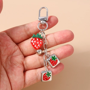 Detailed close-up of a strawberry keychain with resin charm and silver metal square tags