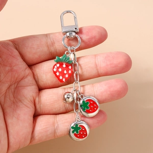 Detailed view of 3D strawberry charm keychain with silver D-clasp held by hand