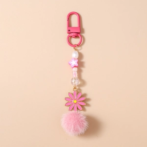 Détail du porte-clés pompon rose avec breloque fleur et sangle perlée élégante