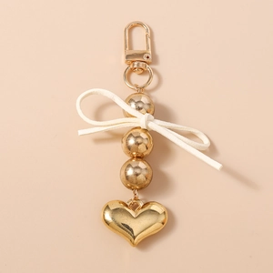 Dettaglio portachiavi a perle dorate con fiocco bianco e pendente a forma di cuore