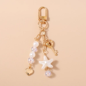 Detail of gold keychain featuring white pearls, colorful beads, starfish, and heart key charms