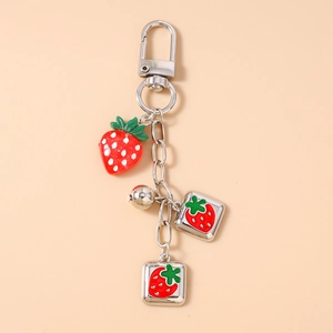 Detail view of 3D strawberry charm keychain with silver ring and square metal tags