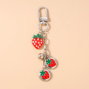 Detailed view of silver strawberry keychain with enamel charm and small bell accessory