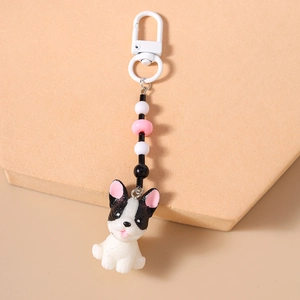 Dettaglio portachiavi bulldog francese con perline e ciondoli rosa su supporto beige