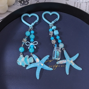 Blue ocean-themed beaded keychains with starfish and fish charms in a dark tray