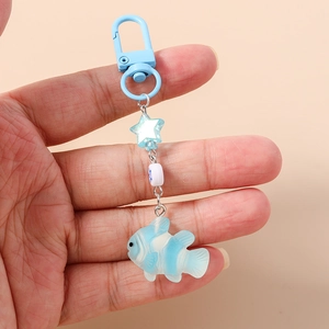 Detail of blue and white striped fish keychain with star charm and bead held by hand