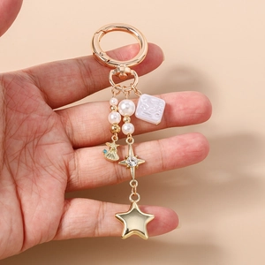 Détail d'un porte-clés doré avec étoiles, perles nacrées et breloque en coquillage
