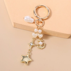 Détails d'un porte-clés ancre doré avec perles blanches, étoile en strass et fermoir chic