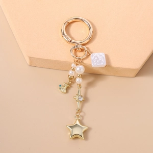Détail d'un porte-clés ancre doré avec perles et pendentifs étoiles sur un support