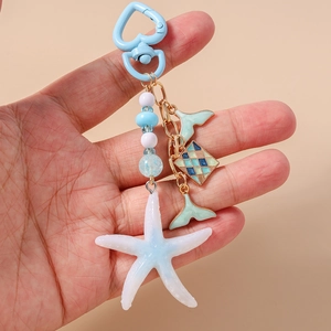 Detail of starfish and fishtail pendants with blue beads on a heart carabiner keychain