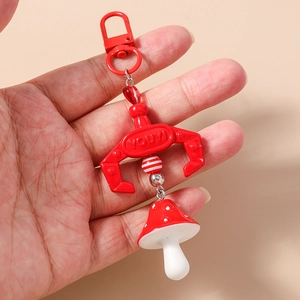 Detail view of a red claw machine keychain featuring a mushroom charm and clasp