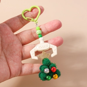 Close-up of a Christmas keychain featuring a plush tree, beaded strap, and plastic claw