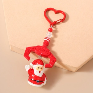 Detail of Santa Claus keychain with red mechanical claw and heart clasp on beige base