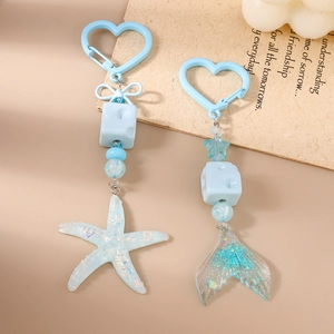 Light blue resin keychain set with sparkling fishtail and starfish charms on a gift card