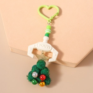 Detail of Christmas beaded keychain featuring mechanical claw holding green plush tree
