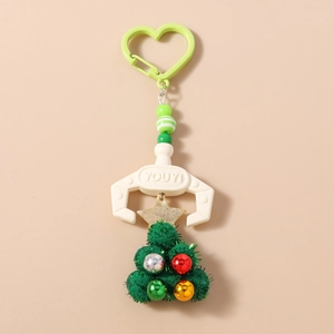 Detail of Christmas tree keychain with green pompoms, gold star and white claw clip charm