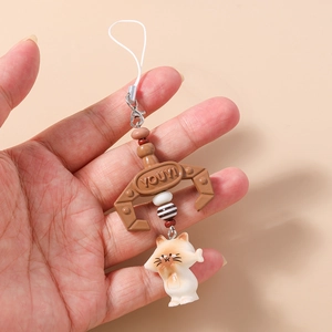 Detail of cute cat phone charm with brown claw hook and white braided strap