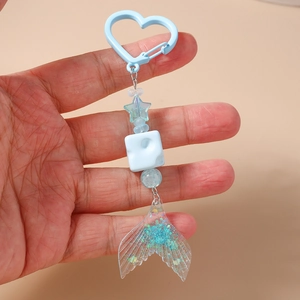 Detailed close-up of a handmade beaded keychain with blue star beads and acrylic fish tail