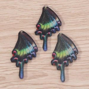 Colorful acrylic butterfly wing pendants for DIY jewelry making on wooden background