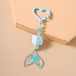 Macro detail of a light blue resin mermaid tail keychain with glitter finish and star charm