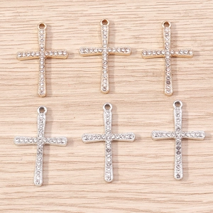 Detailed view of pavé crystal cross pendants in polished gold and silver finishes