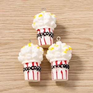 Vue détaillée de trois breloques de pop-corn 3D avec boucles en métal sur bois