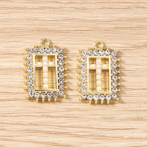 Close-up of gold rectangular pendants featuring pearl crosses and sparkling zircons
