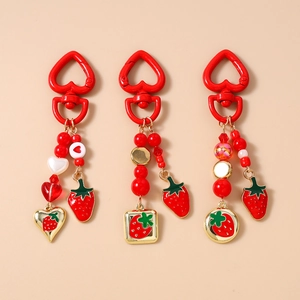 Detail of red beaded strawberry keychain set with heart-shaped hooks and gold charms