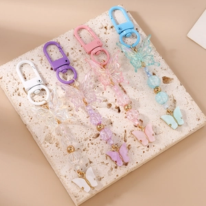 Detailed close-up of four colorful beaded butterfly keychains on stone display plate