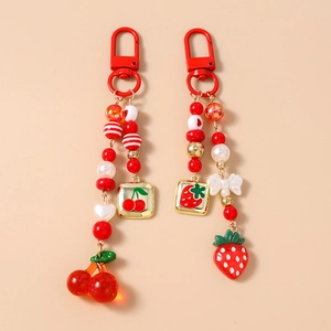 Detailed view of beaded strawberry and cherry keychains with cute resin charms and bows
