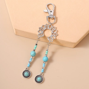 Détail d'un porte-clés bohème avec perles turquoise, breloque lotus et médaille fleurie