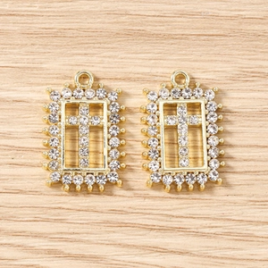 Macro detail of gold rectangle cross charms with clear rhinestones for DIY jewelry
