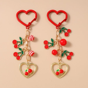 Detail of red enamel cherry pendants with gold chains and heart carabiners on keychains