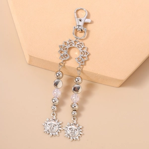 Détail du fermoir mousqueton argenté avec pendentifs soleil et chaîne perlée pour porte-clés