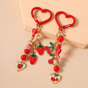 Close-up of strawberry and cherry fruit charms with red beads on a heart-shaped clasp