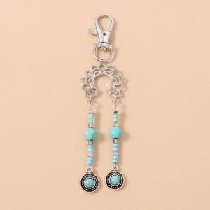 Détail d'un porte-clés bohème avec perles turquoise, ornement lotus et breloques argentées