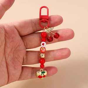 Close-up of handmade beaded cherry keychain with red heart charms and gold carabiner