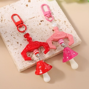 Pink and red beaded mushroom claw crane keychains on a natural stone surface