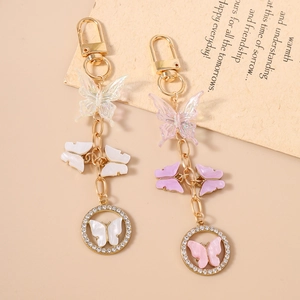 Detail of pearlescent butterfly keychains with gold lobster clasps and rhinestone charms